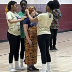 Artist In the Middle presenters dressing one of our students in African dress